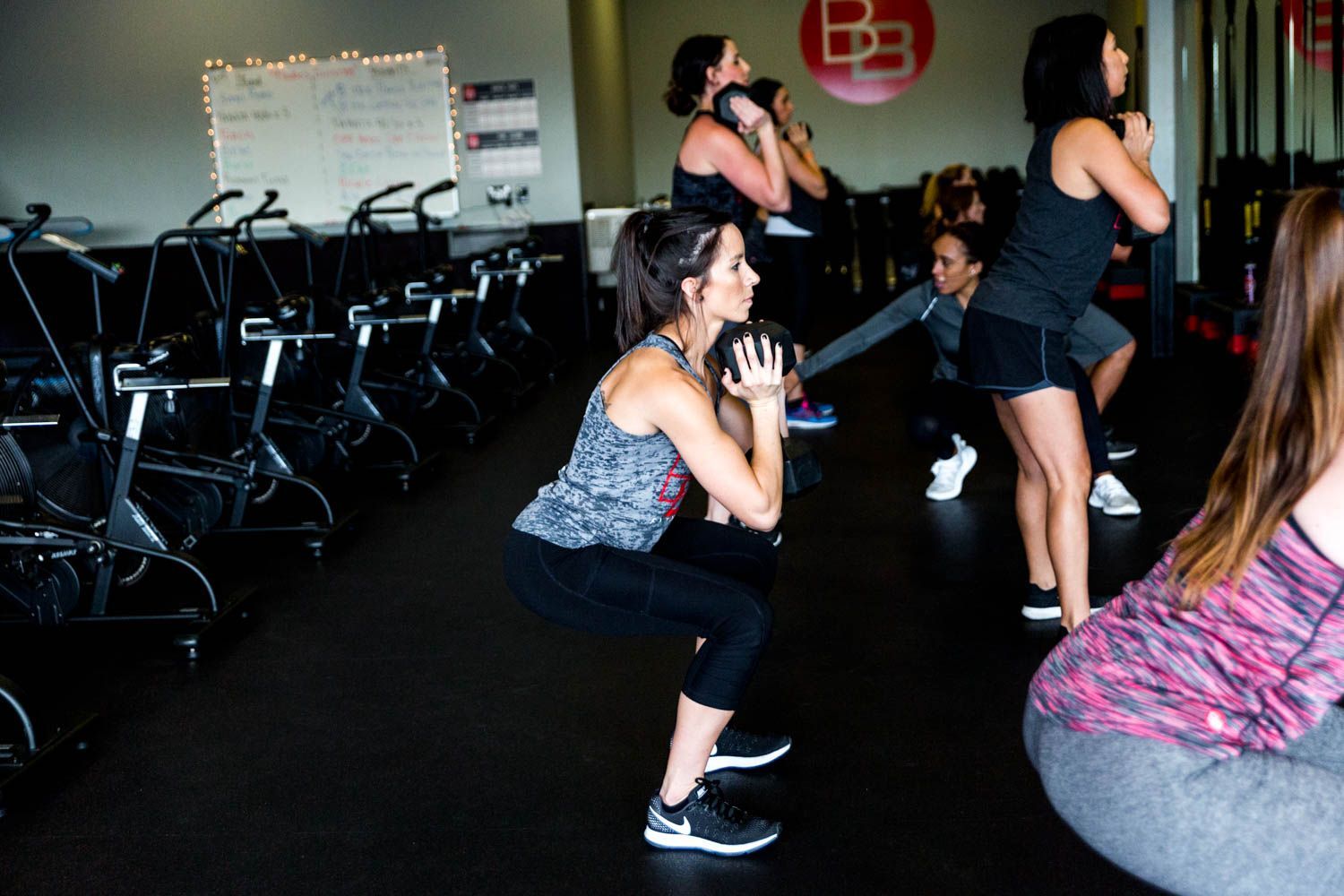 Women doing squats with weights in a gym.