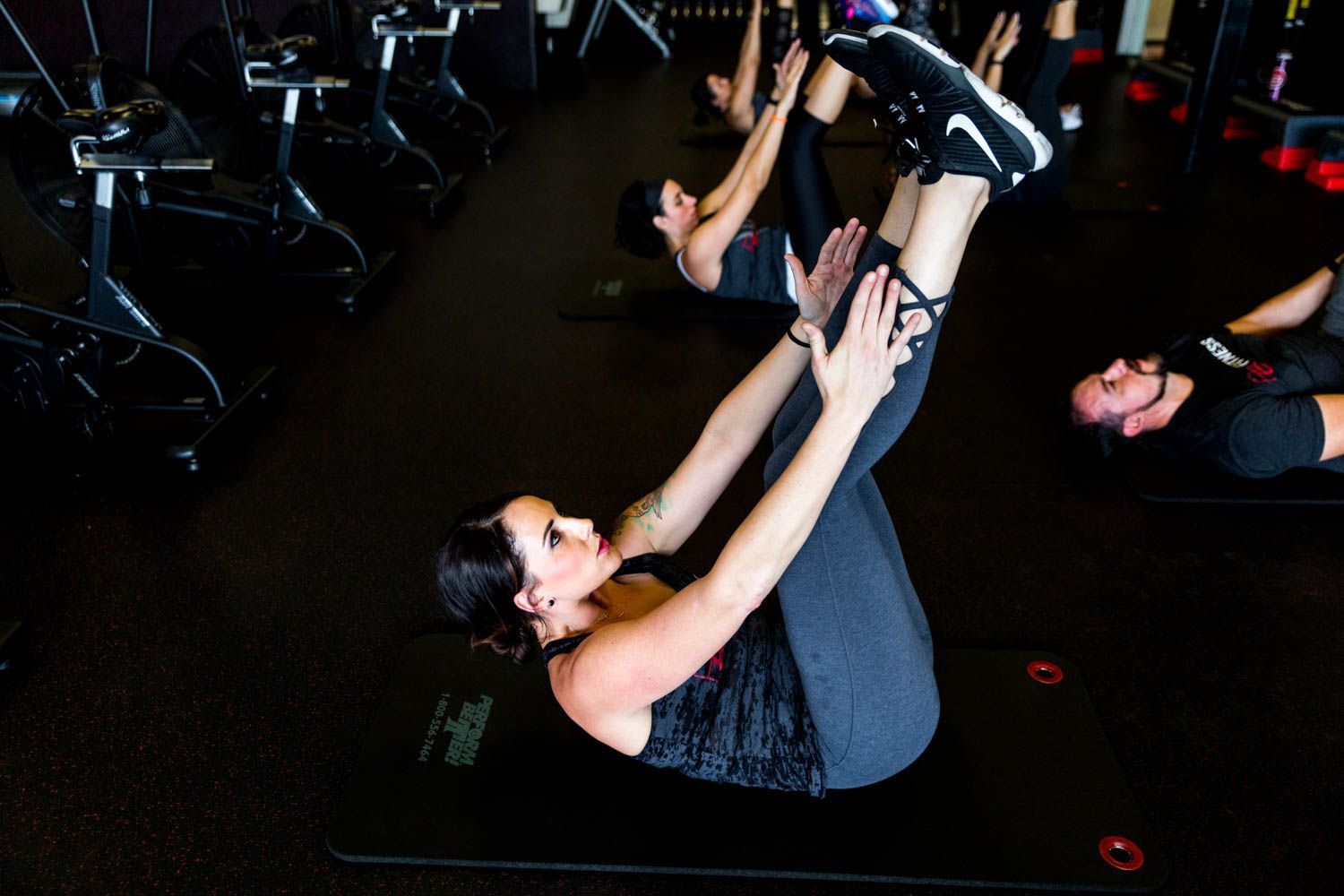 People doing core workout on mats in a dark gym.