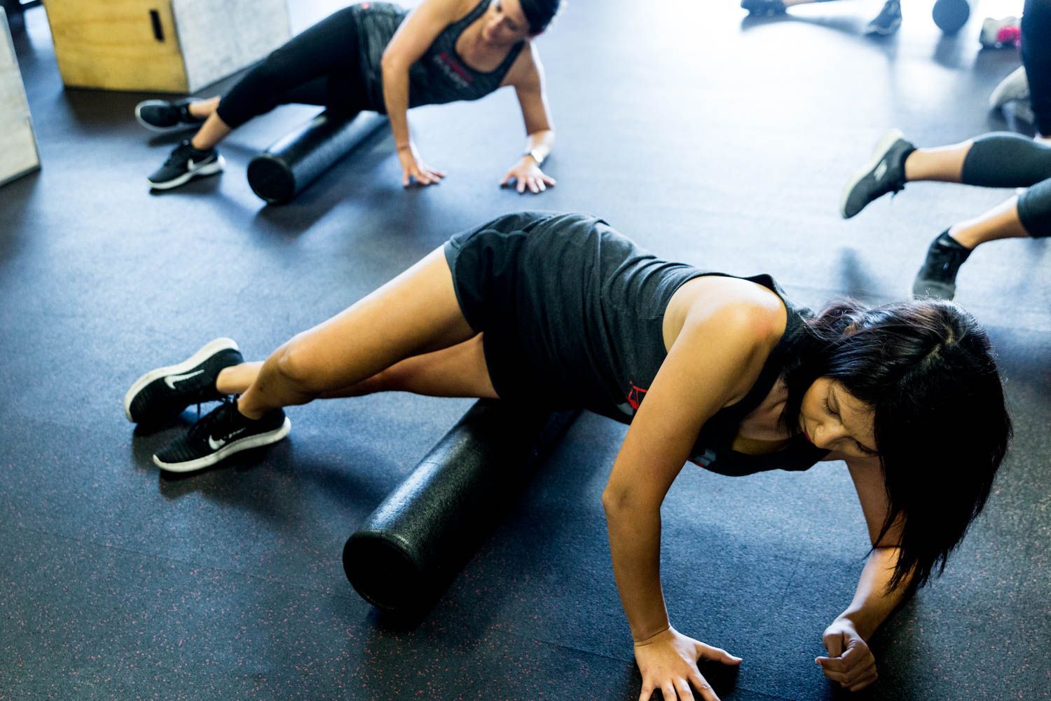 People in a gym performing side plank on a foam roller.