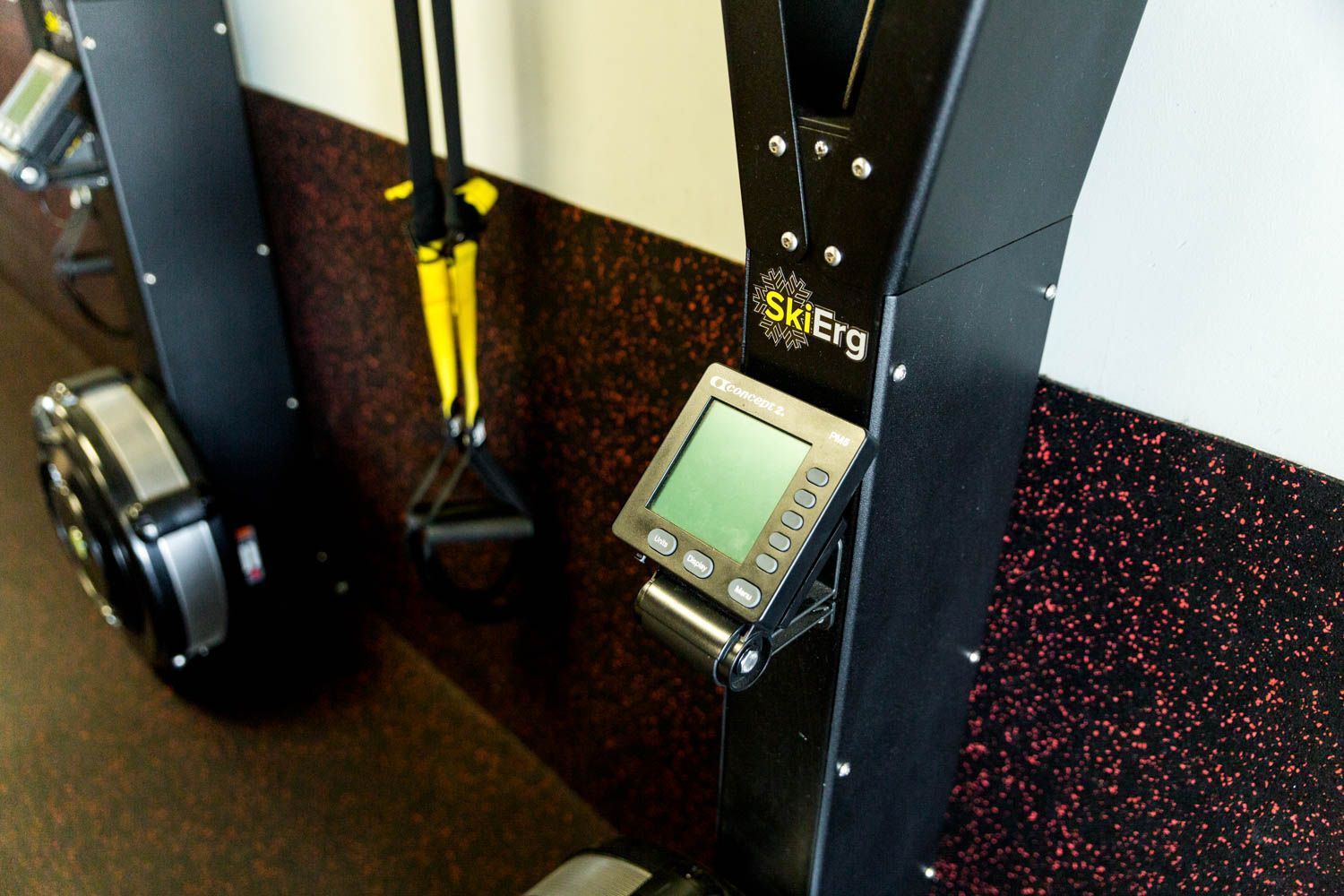Close-up of a SkiErg machine with a digital display attached to a wall. The machine has black components.