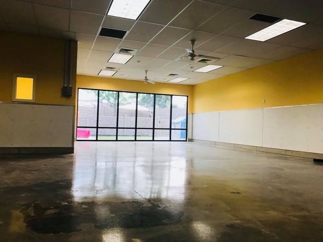 Empty room with yellow walls, white tile floor, and large windows at the far end