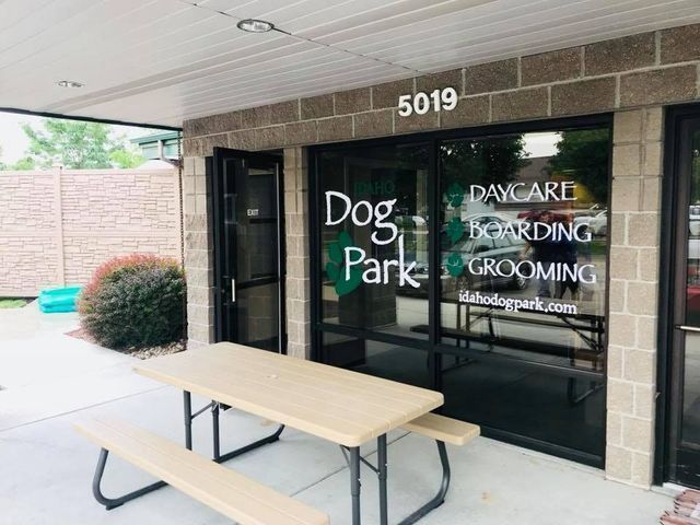 Dog Park storefront with glass door, daycare and grooming signs, and a picnic table outside
