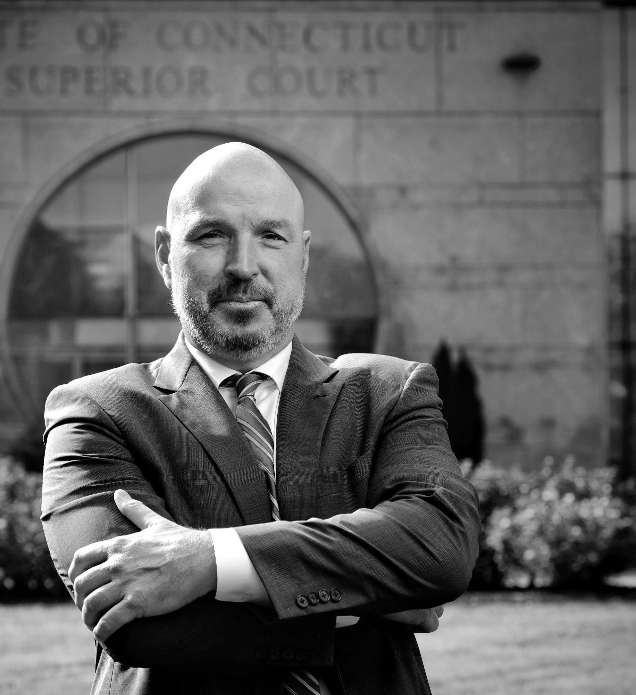 Sol Mahoney in a suit and tie is standing in front of a building that says superior court