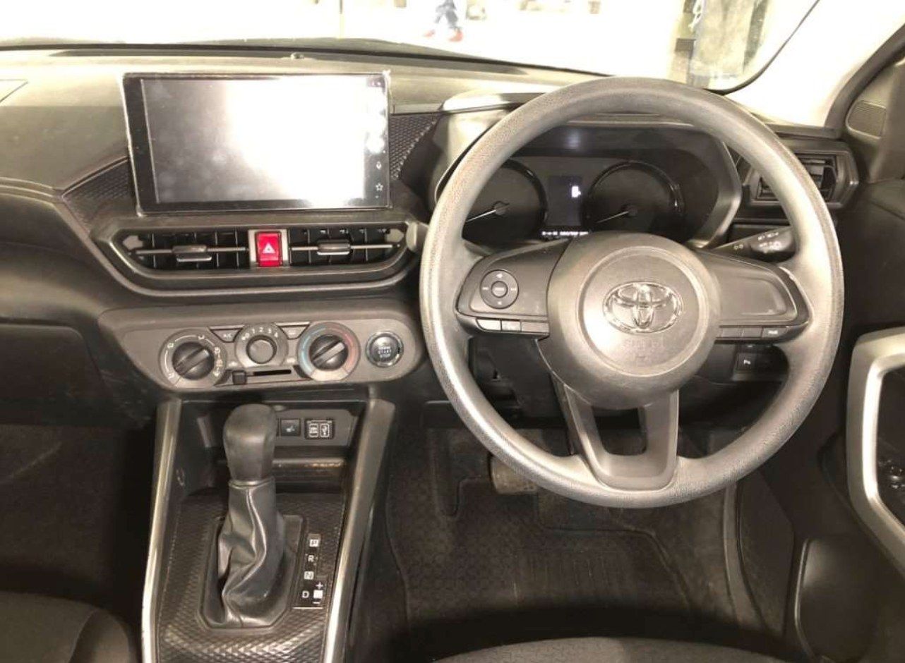 Interior of a gray car dashboard featuring a steering wheel, infotainment screen, and gear shift.