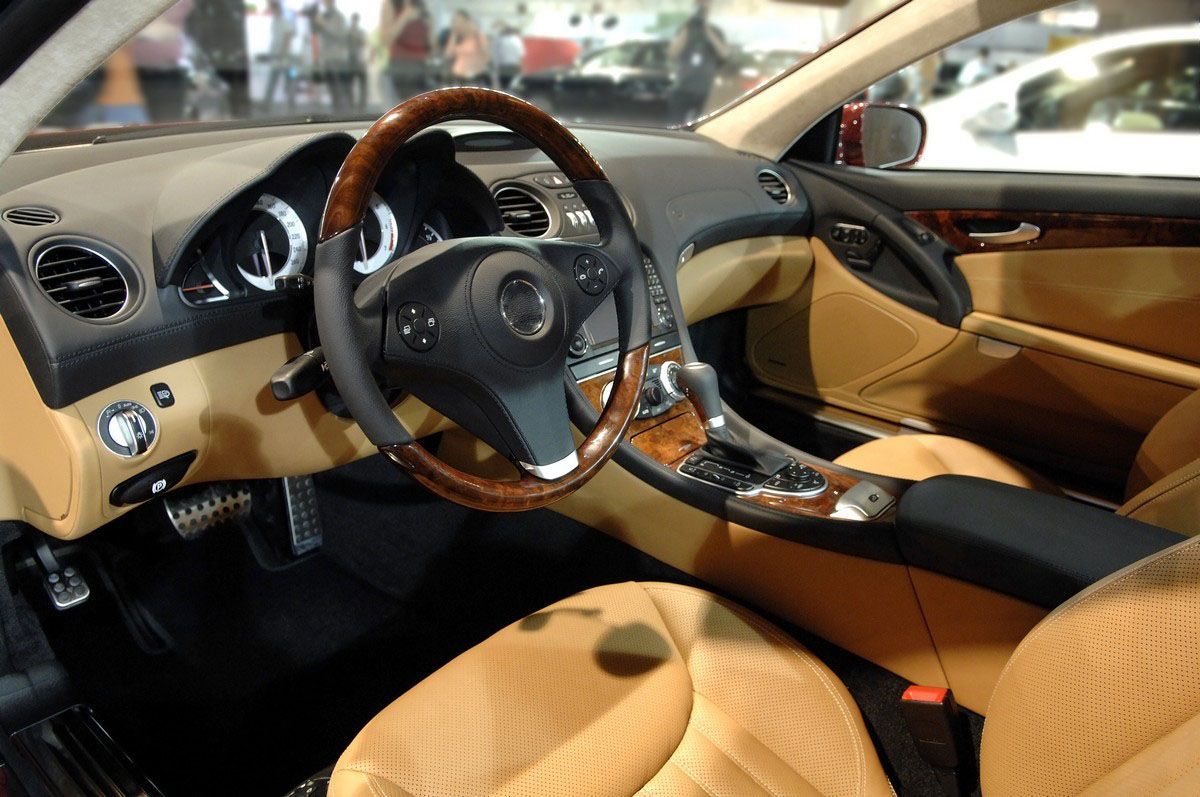 Interior of a gray car dashboard featuring a steering wheel, infotainment screen, and gear shift.
