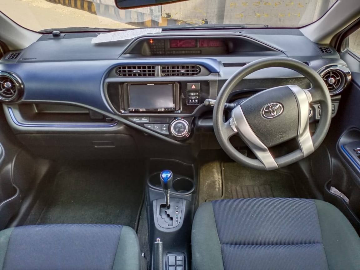 Interior view of a Toyota Aqua car, featuring a blue dashboard, steering wheel, and center console.