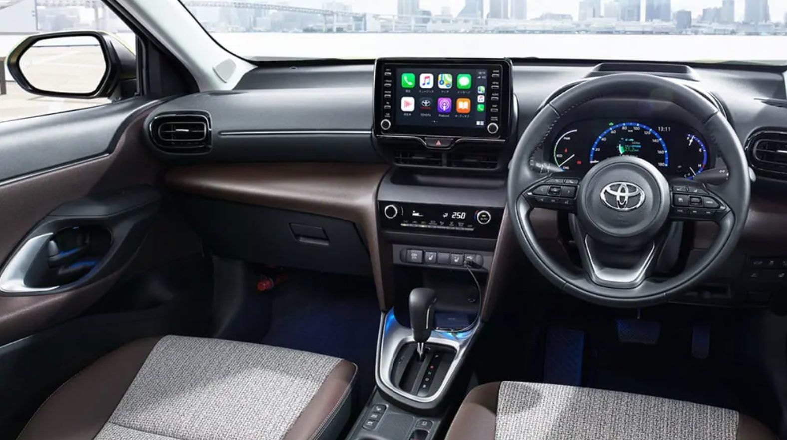 Interior of a Toyota Yaris: dashboard with touchscreen display, steering wheel, brown and gray accents.
