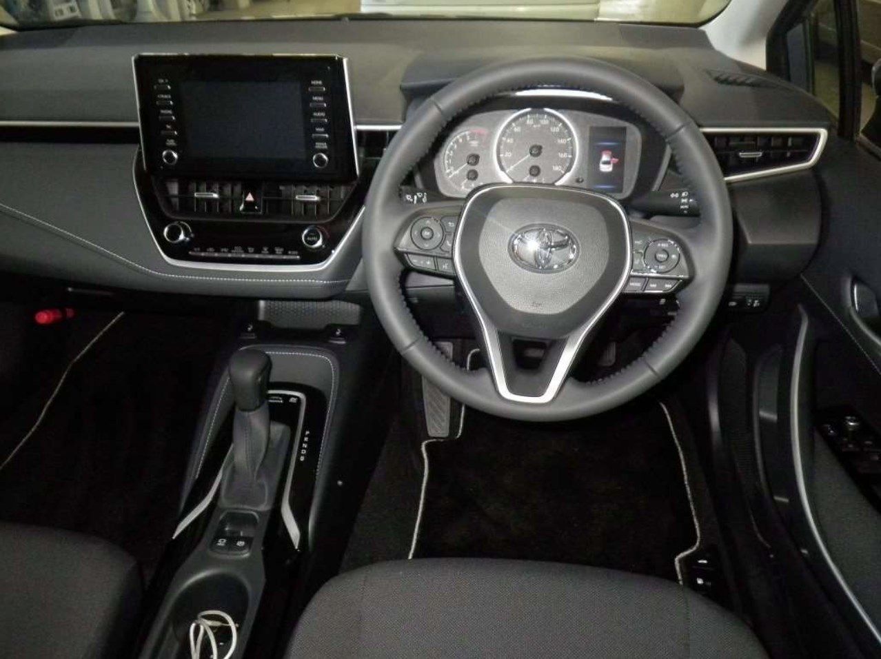 Black Toyota Corolla interior with dashboard, steering wheel, and gear shift.