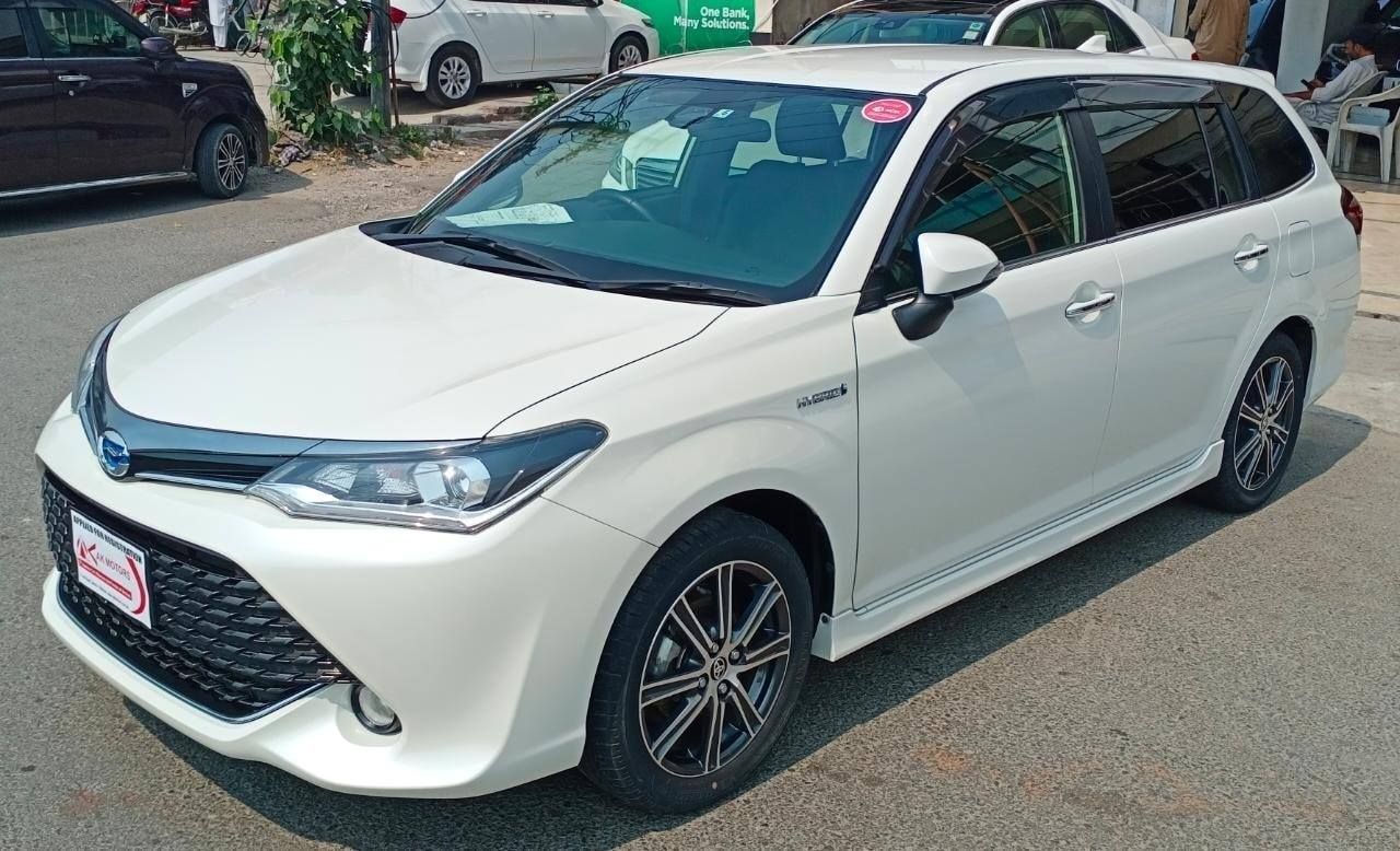 White Toyota Corolla Fielder hybrid wagon parked on asphalt.