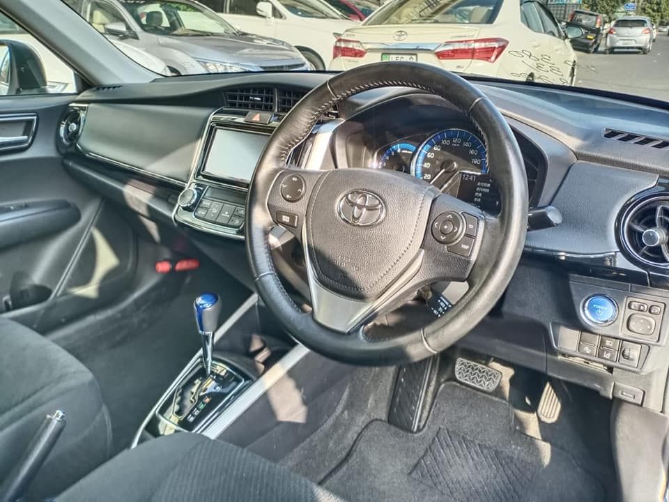 Interior of a car with a black steering wheel, dashboard, and gear shift.