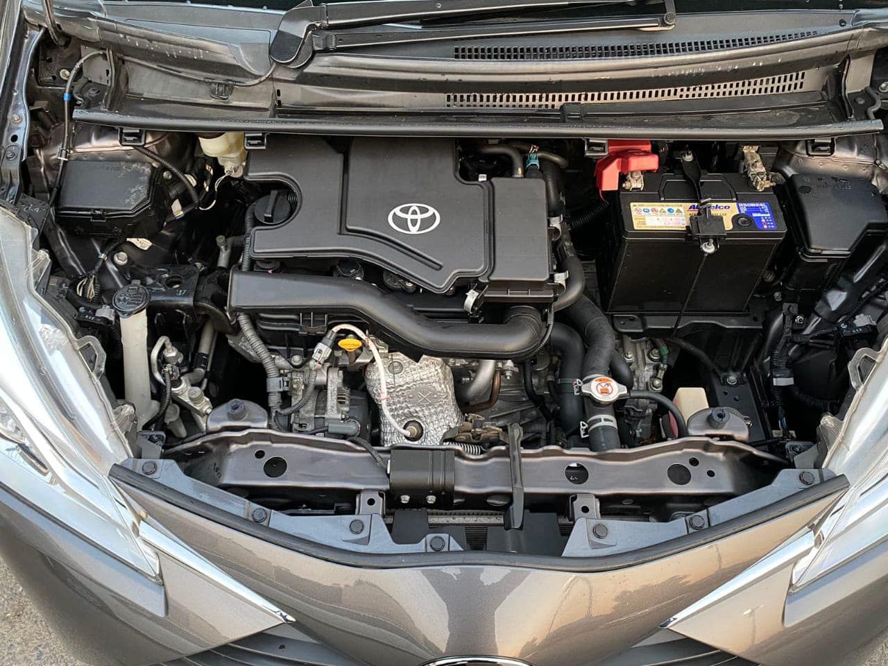 Car engine compartment with Toyota engine. Black and gray components visible.