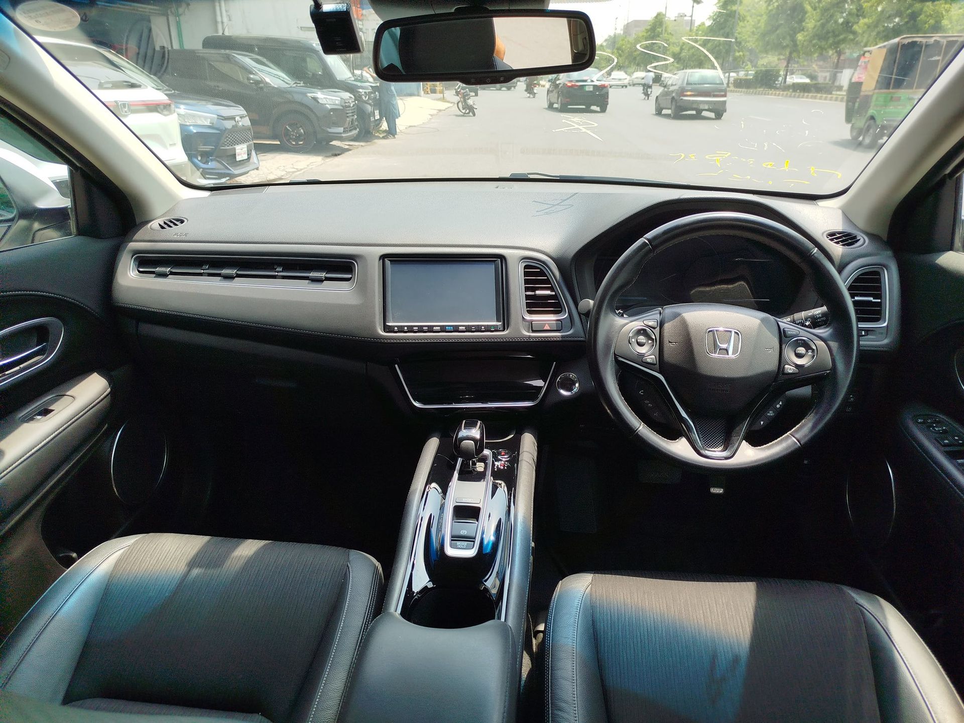 Interior of a Honda HR-V car, featuring dashboard, steering wheel, seats, and a view of the road outside.