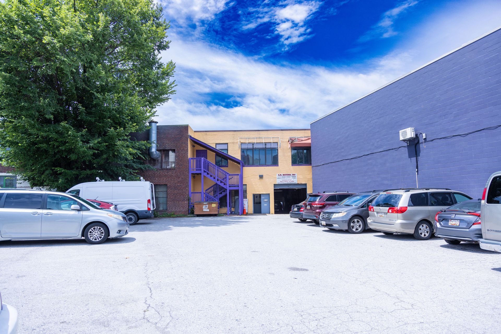 Parking lot with parked cars, and buildings under a blue sky.