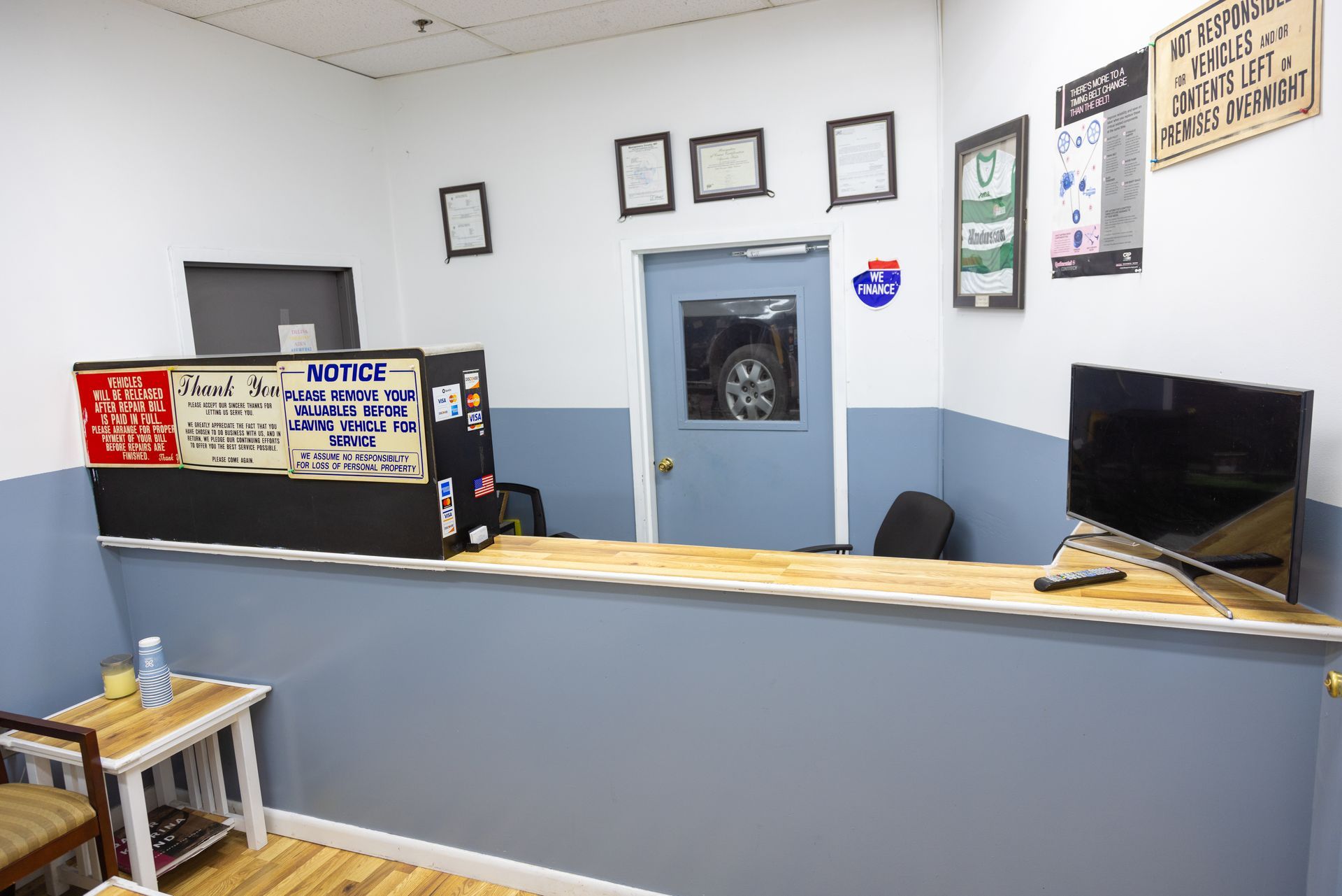 Reception area with counter, waiting area, and door to a shop area. Blue and beige walls.