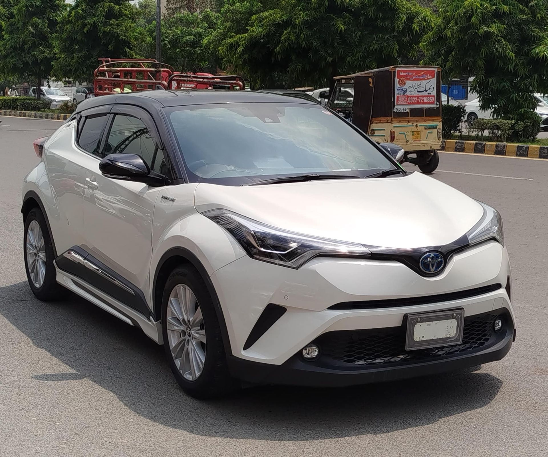 White Toyota C-HR compact SUV with a black roof, parked on a road.