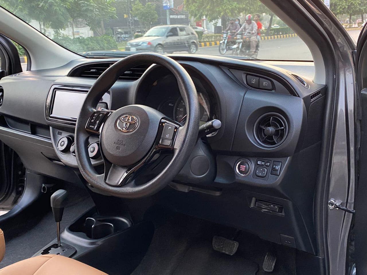 Interior view of a black Toyota Yaris car showing steering wheel, dashboard, and infotainment screen.