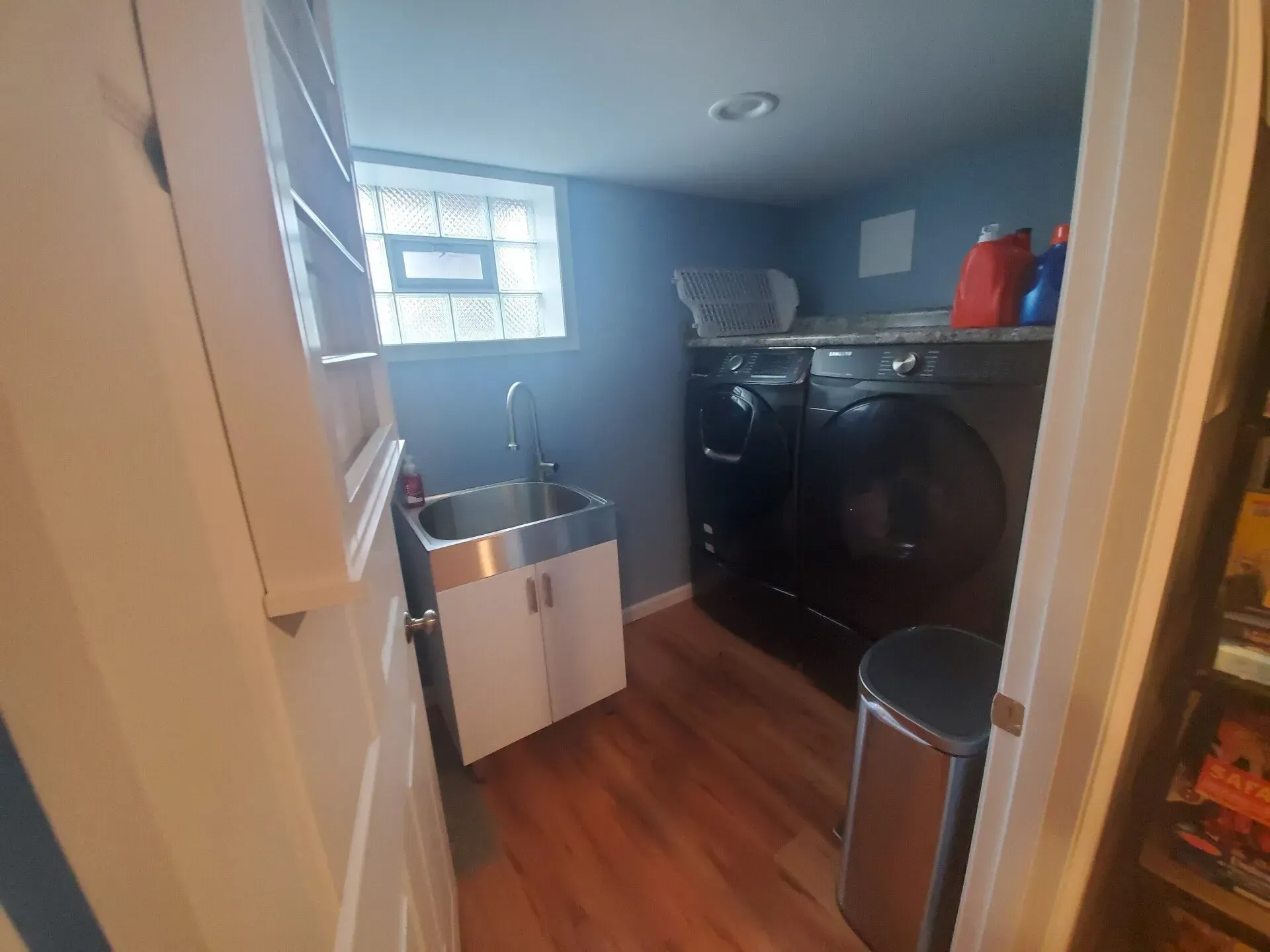 Laundry room with dark washer/dryer, sink, and wooden floor.