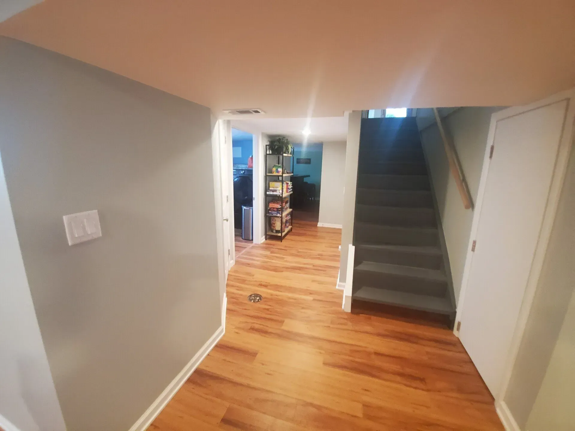 Hallway with wood floors, light gray walls, stairs, and doors.