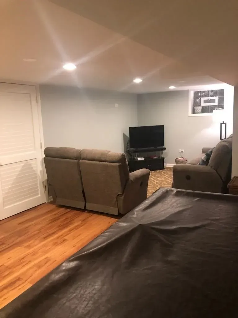 Basement living area with recliner seating, TV, and wood floor. 