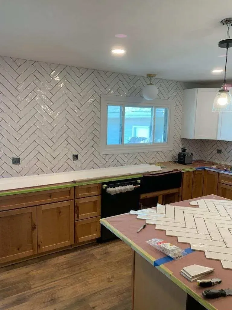 Kitchen with herringbone tile backsplash and wooden cabinets.