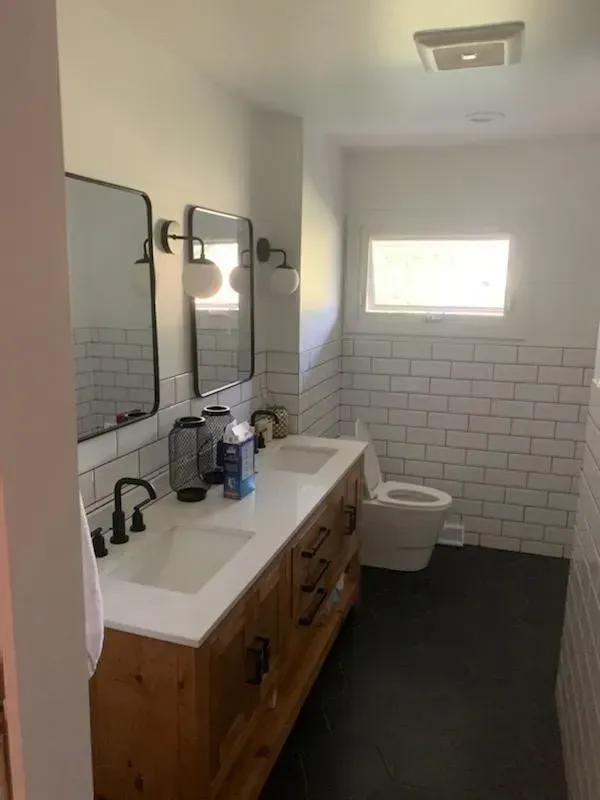 Modern bathroom with white subway tile, dark wood vanity with double sinks, and black fixtures.
