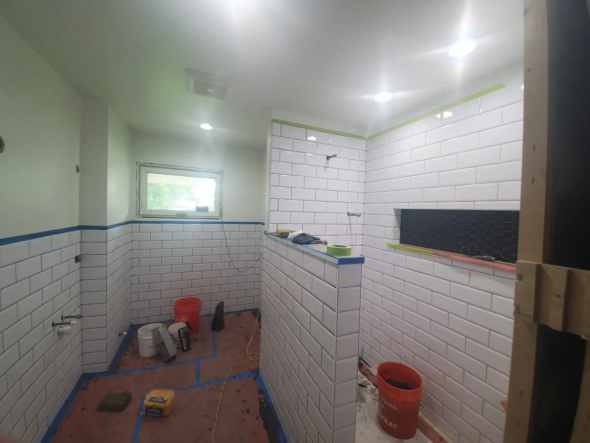 Bathroom under construction with white subway tiles on walls. 
