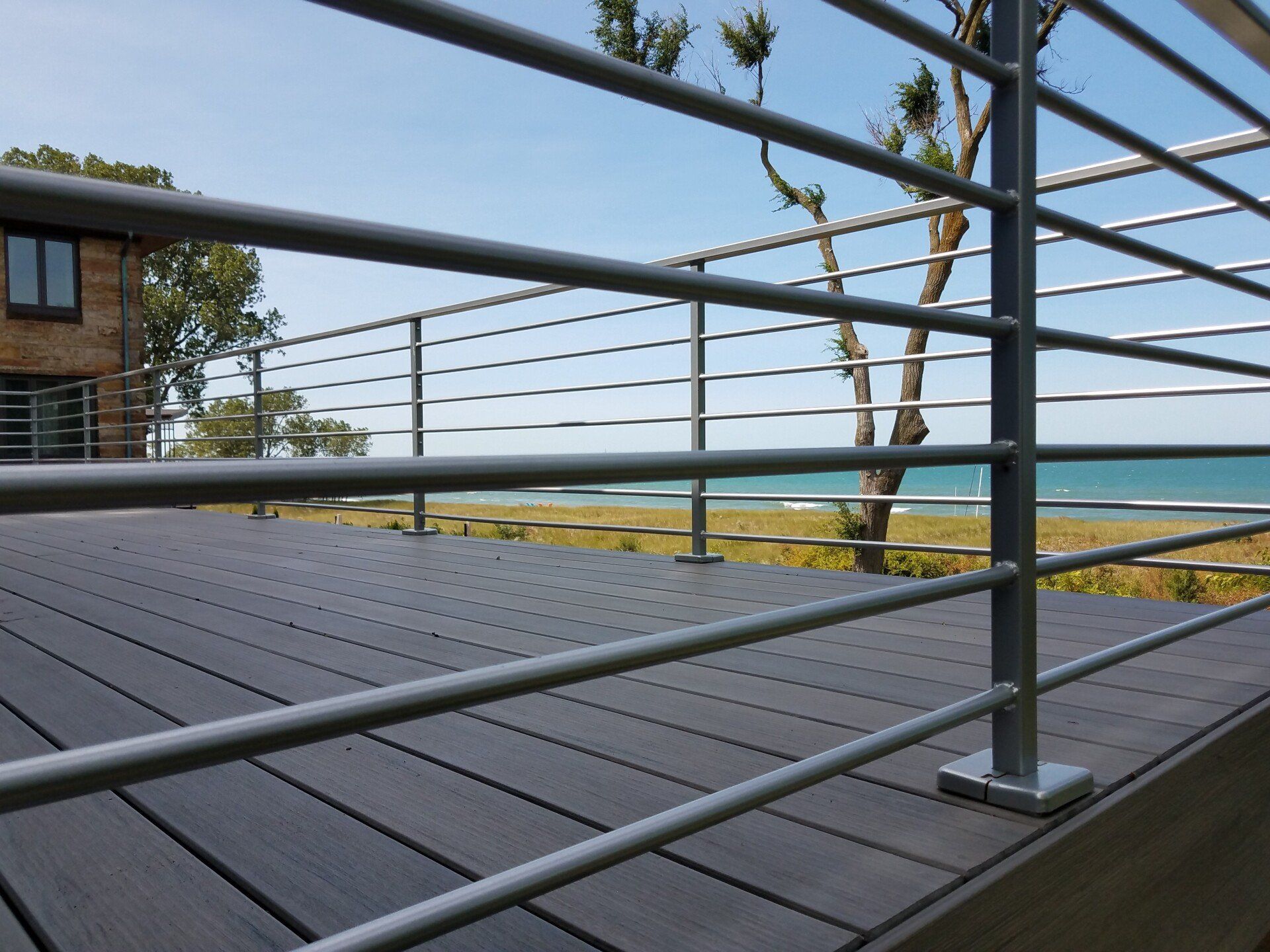 Gray deck with metal railing overlooking ocean.