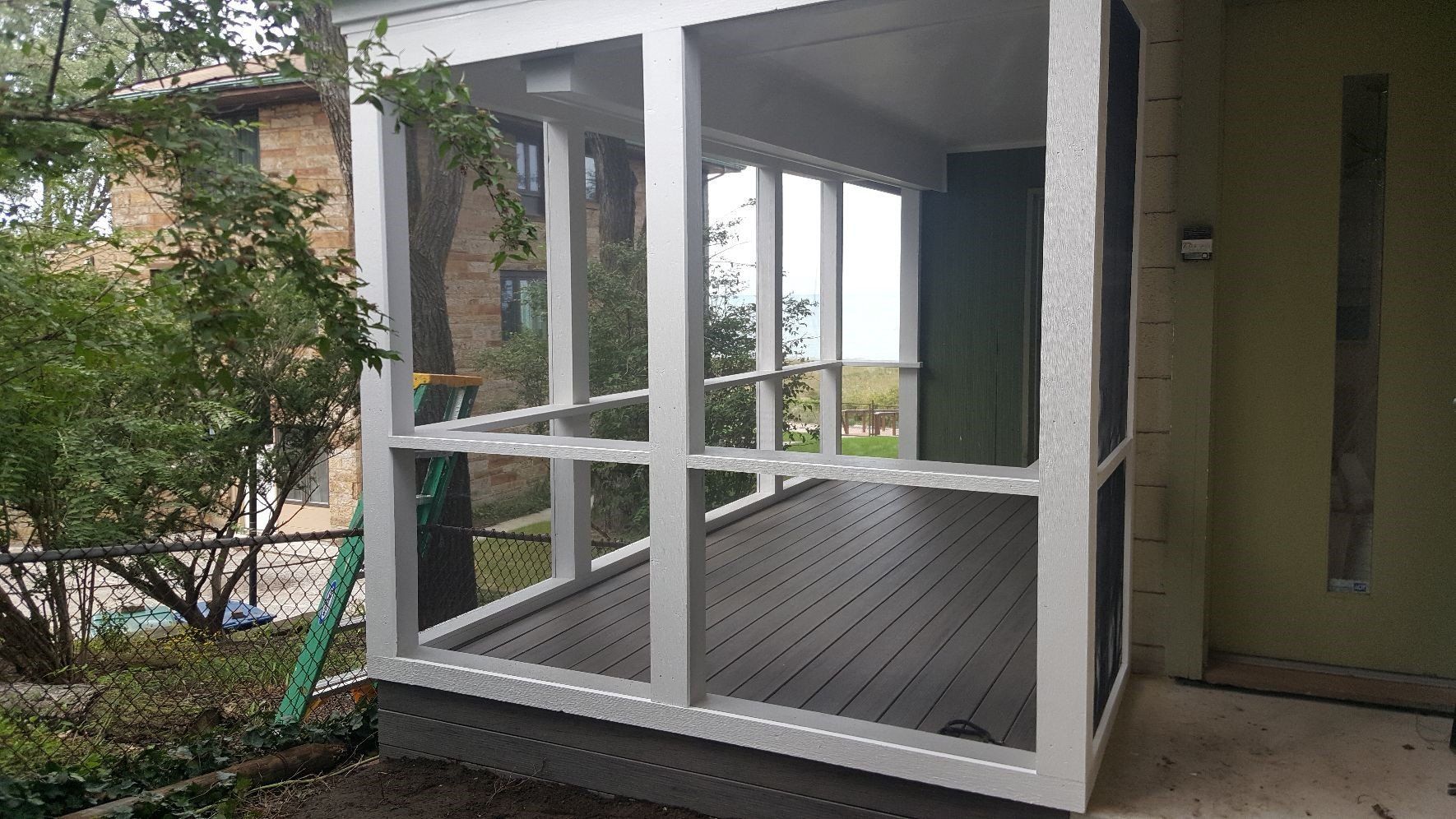 Screened-in porch with white framing, gray composite deck, and green walls.