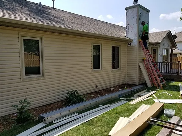 House exterior with siding being installed; workers on a ladder.