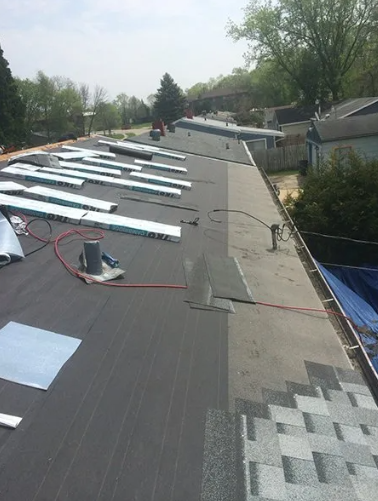 Roof partially covered with black underlayment and gray shingles during installation.