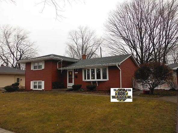 Red-sided ranch home with white trim and bare trees under a cloudy sky. Sign in yard.