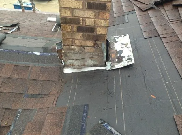 Chimney with deteriorating flashing on a shingled roof.