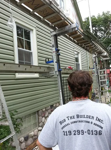 Man in Bob the Builder shirt standing near house with scaffolding.