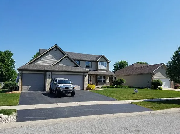 Two-story house with a Hummer parked in the driveway on a sunny day.