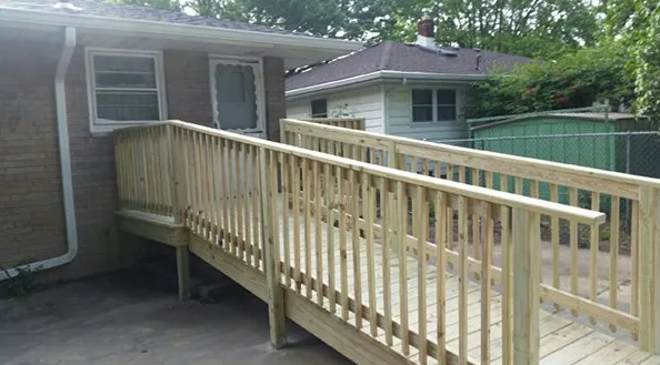 Wooden wheelchair ramp leading up to a residential building's door.