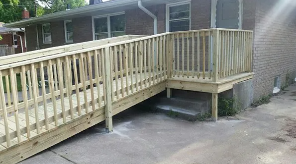 Wooden ramp and deck attached to a brick house for accessibility.