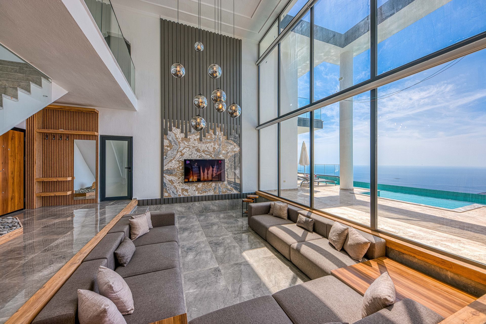 Modern beachfront living room with floor-to-ceiling windows, fireplace, and ocean view
