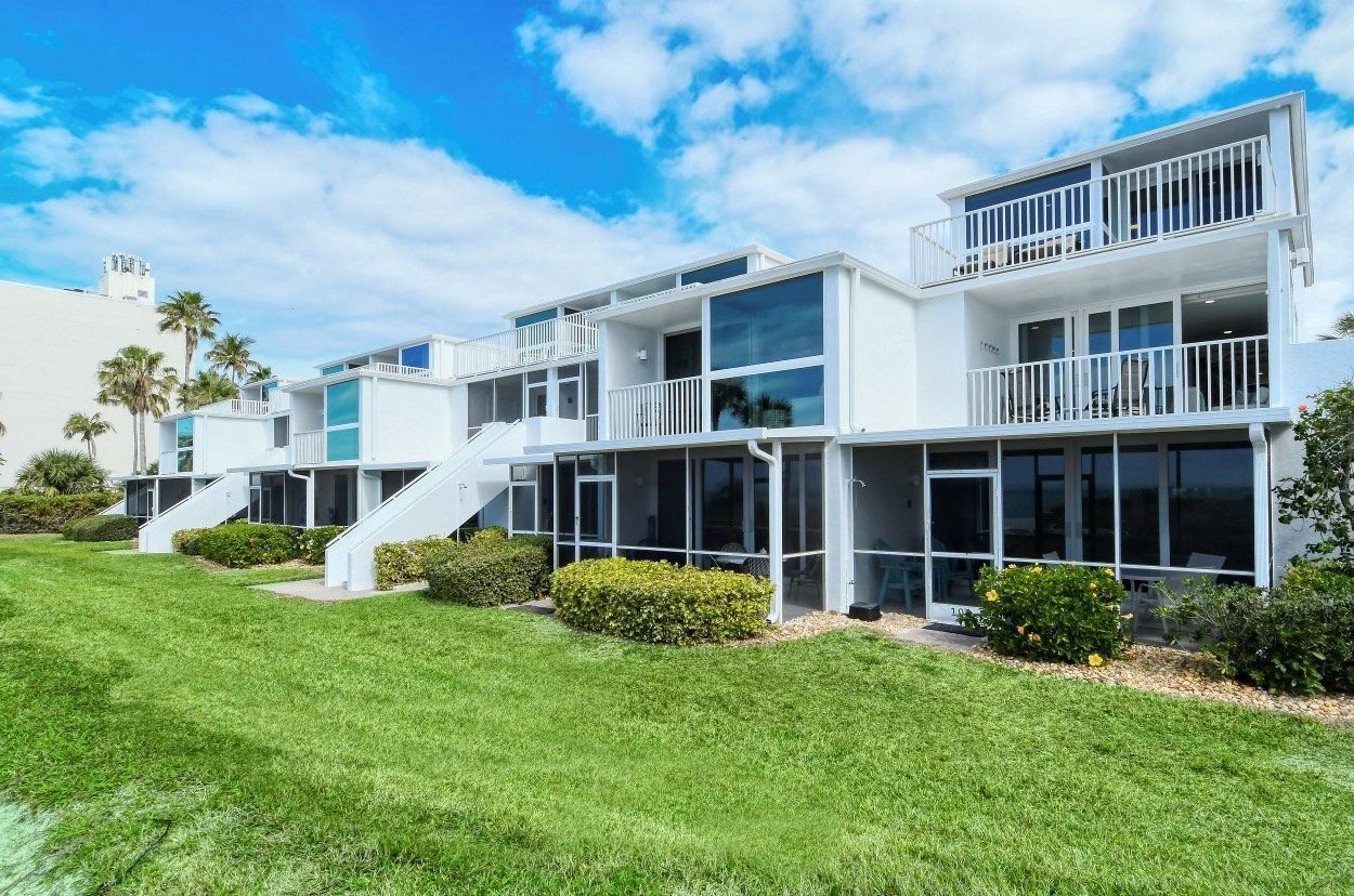 A row of white houses sitting next to each other on a lush green lawn.