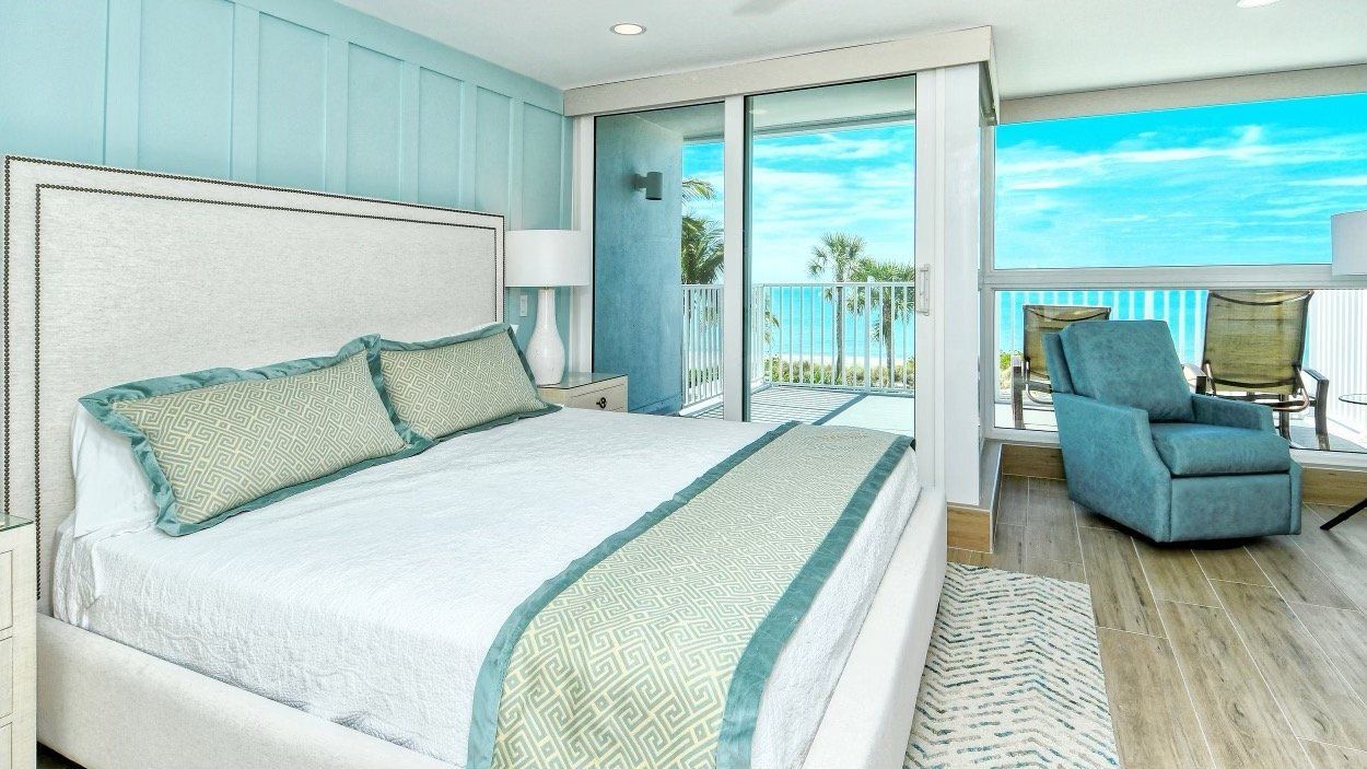 There is a large bed in the middle of the room with a view of the ocean.