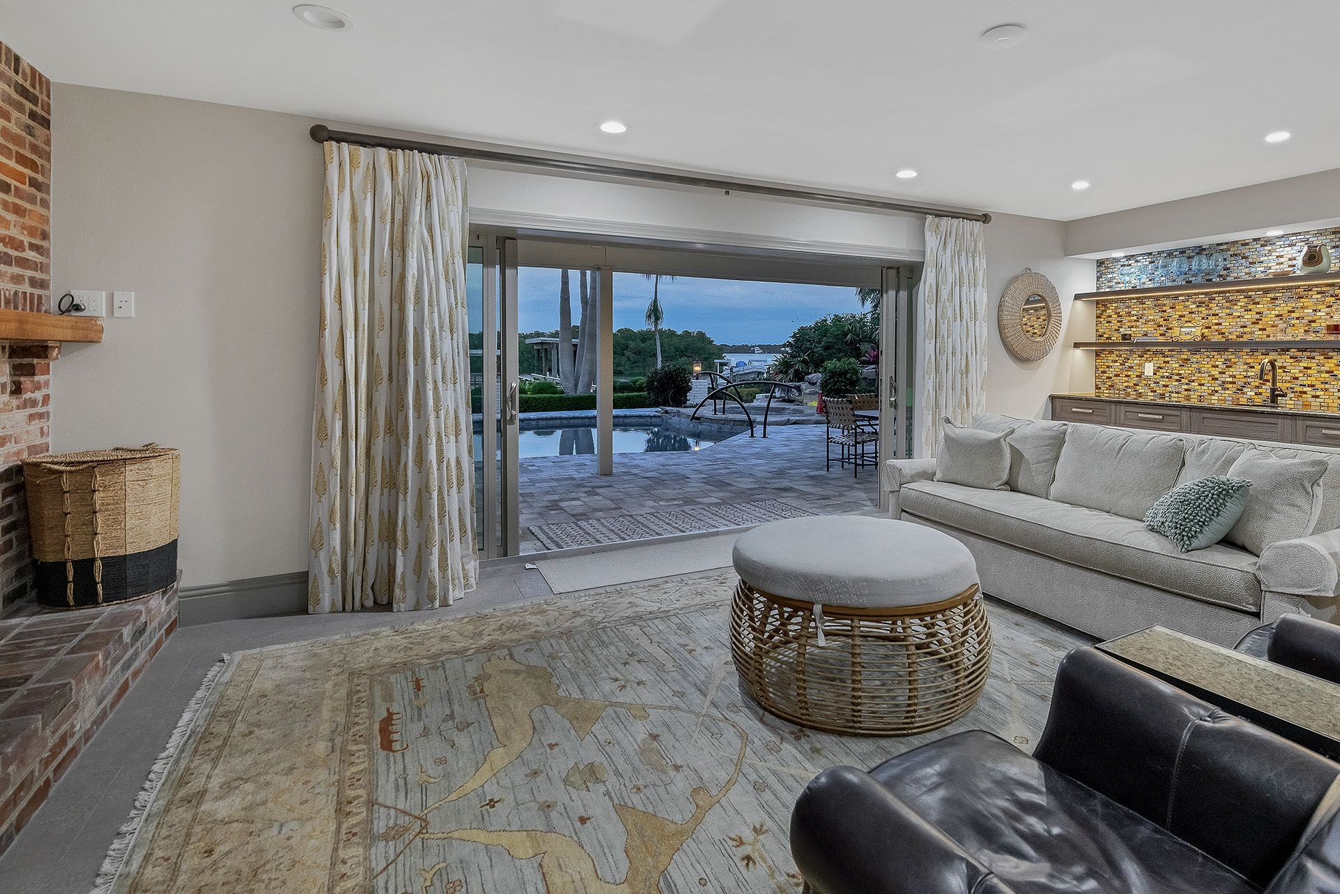 A living room with a couch, chairs, ottoman, and sliding glass doors leading to a patio.