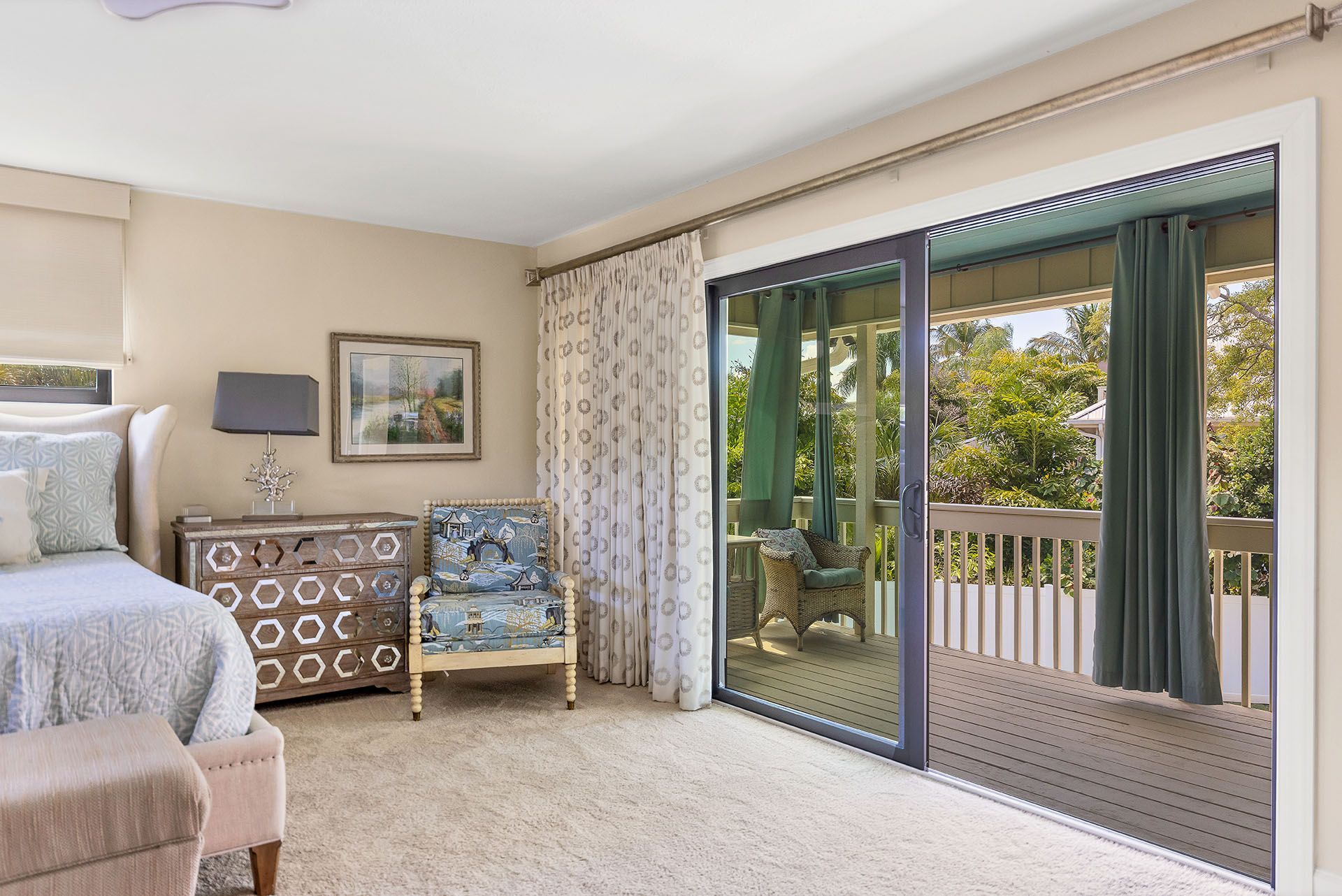 A bedroom with a bed, chair, dresser, and sliding glass doors leading to a balcony.