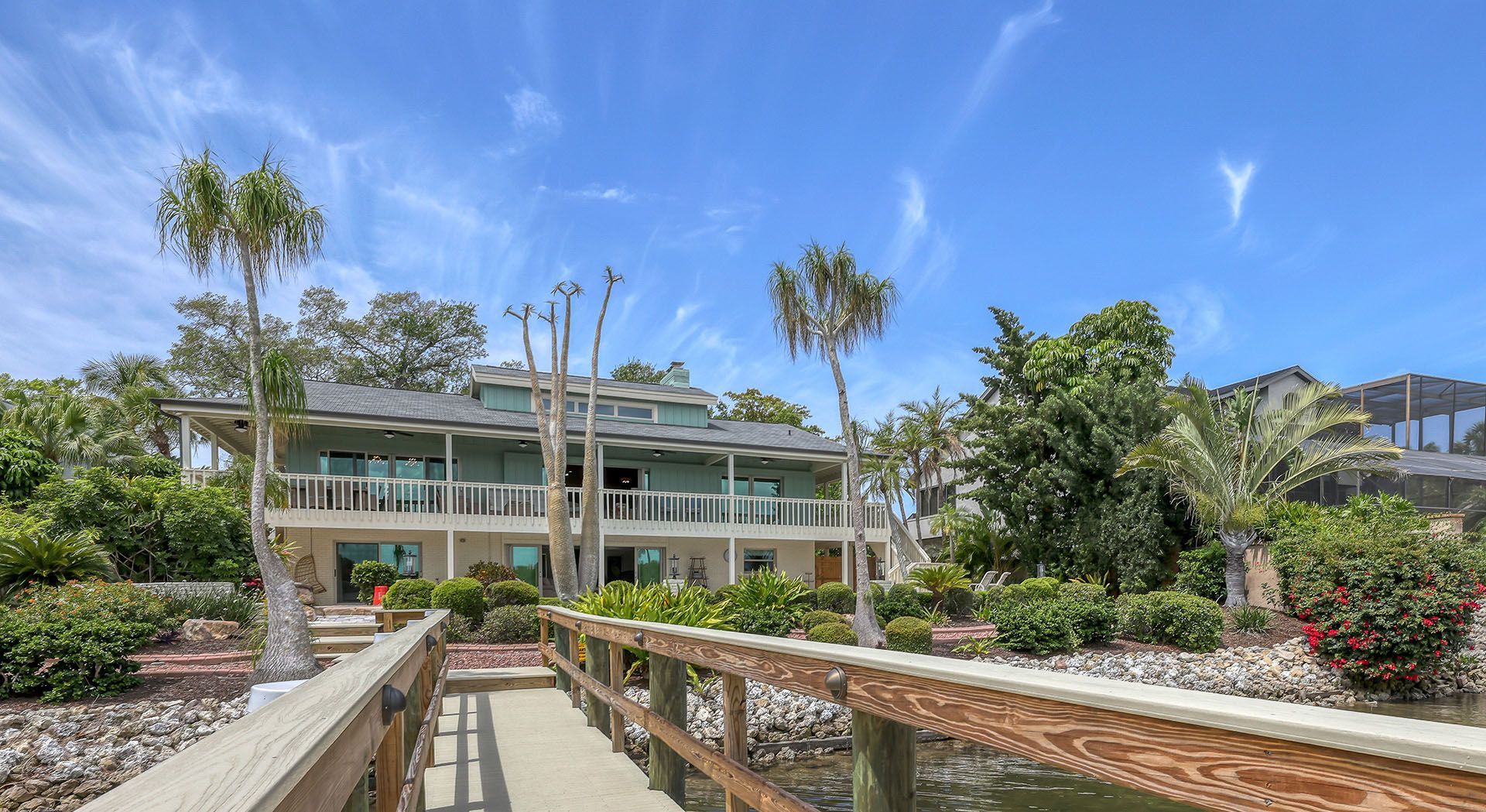 There is a wooden bridge leading to a large house.