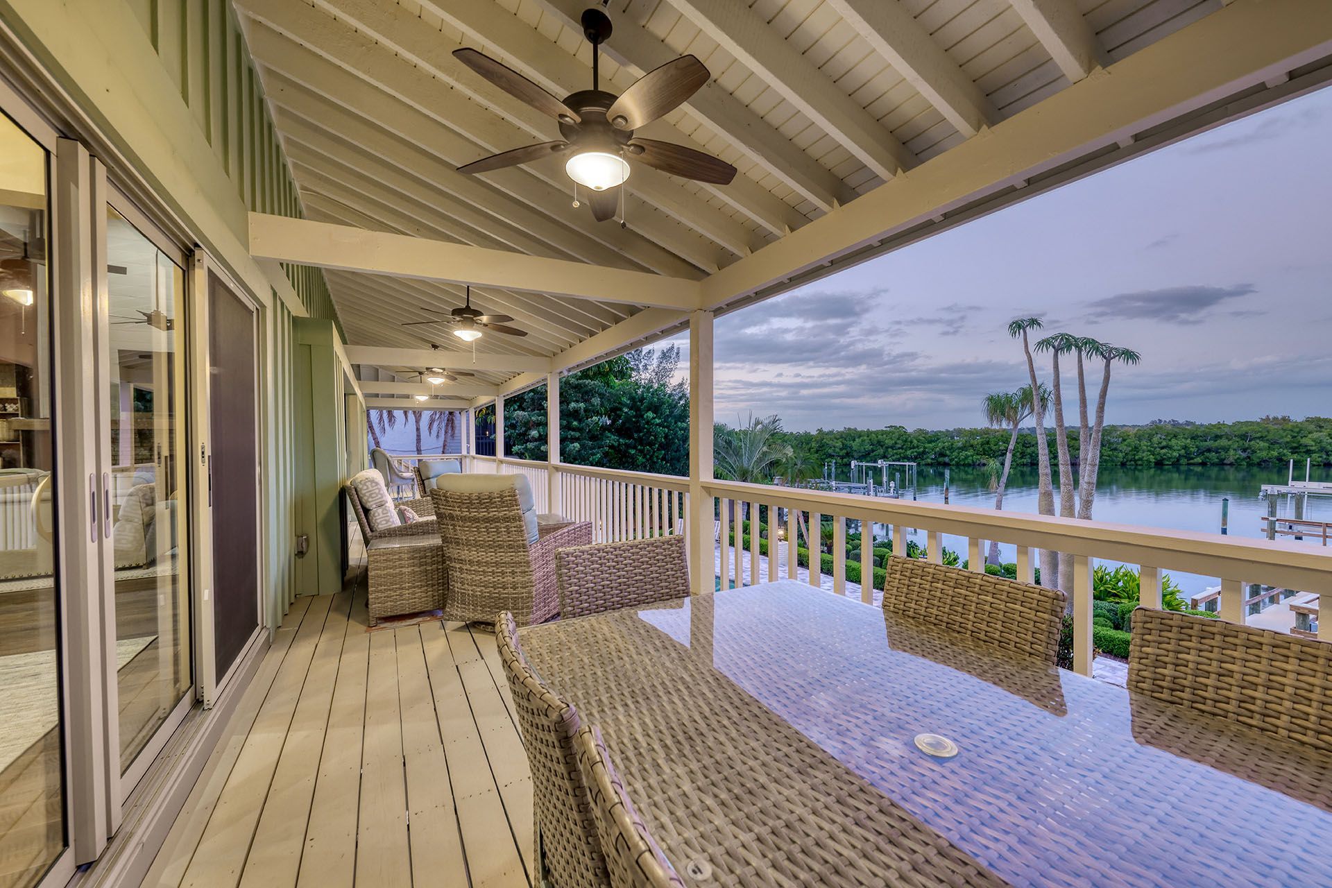 A large porch with a table and chairs overlooking a body of water.