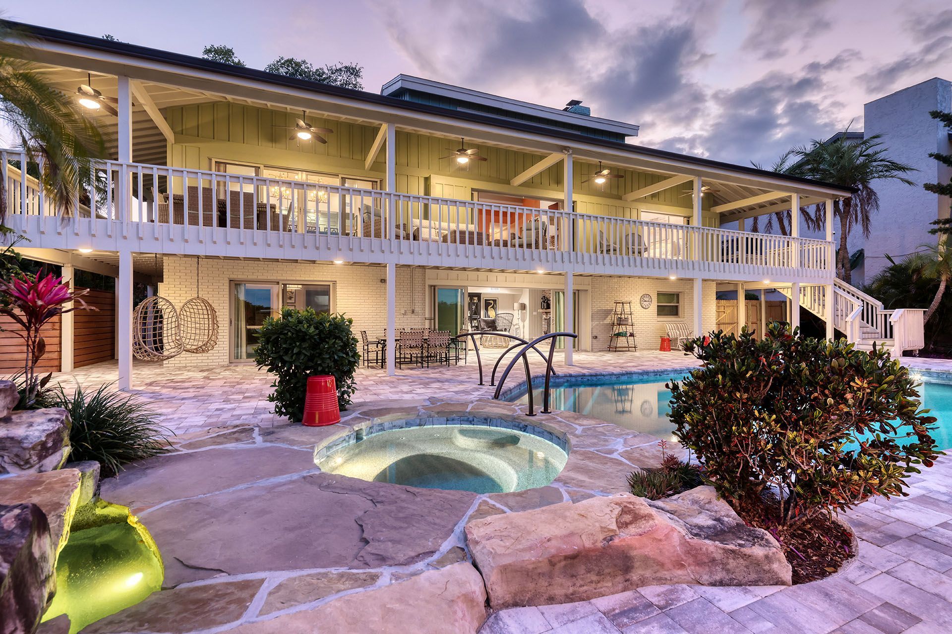 A large house with a swimming pool and a hot tub in front of it.
