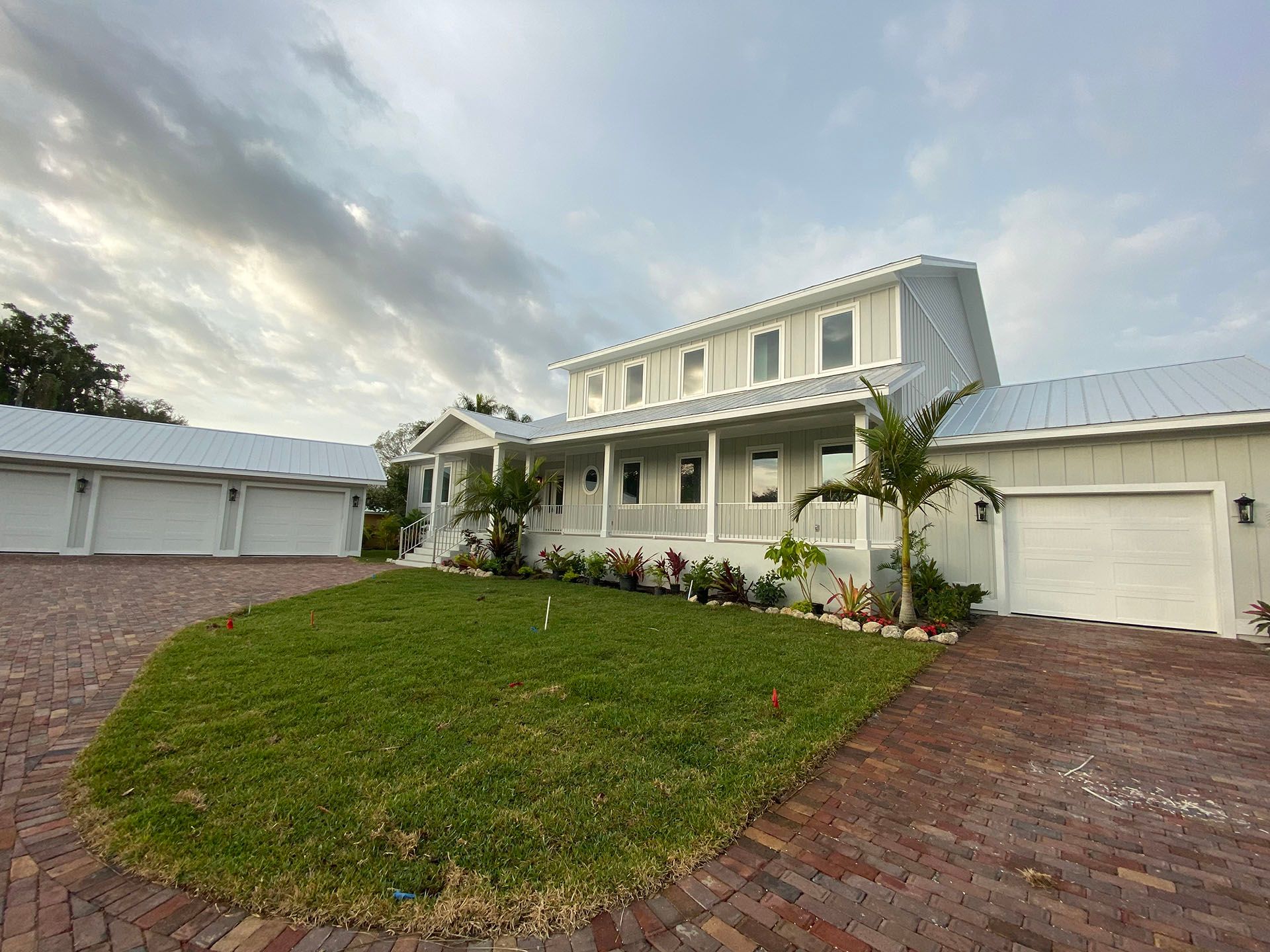 A large white house with a brick driveway in front of it.