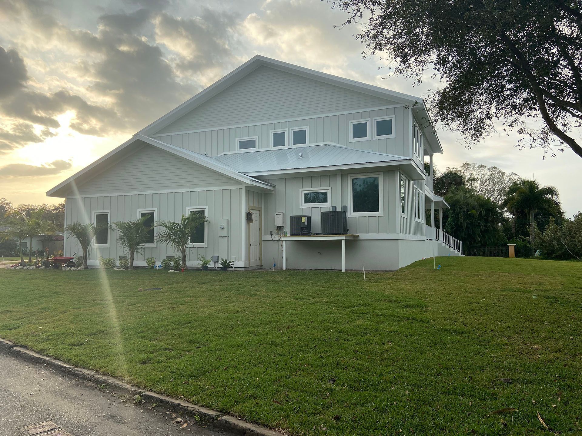A large white house is sitting on top of a lush green hill.