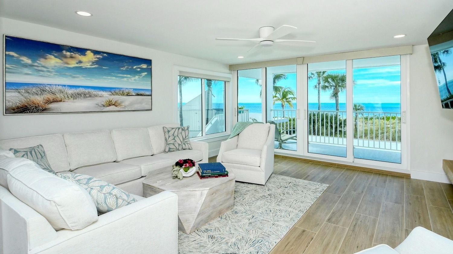 A living room with a couch, chairs, and a table with a view of the ocean.