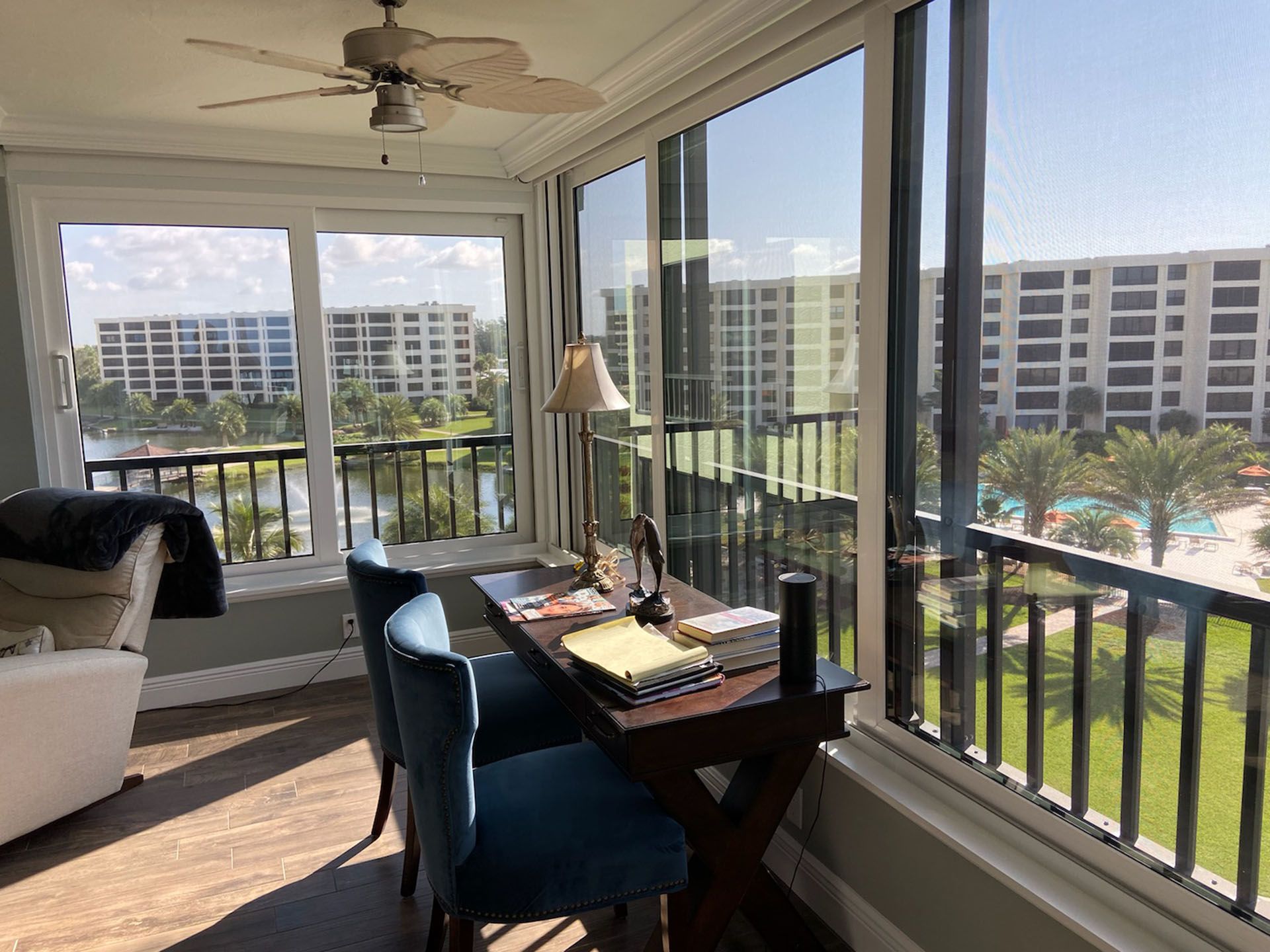 A room with a desk , chairs and a ceiling fan.