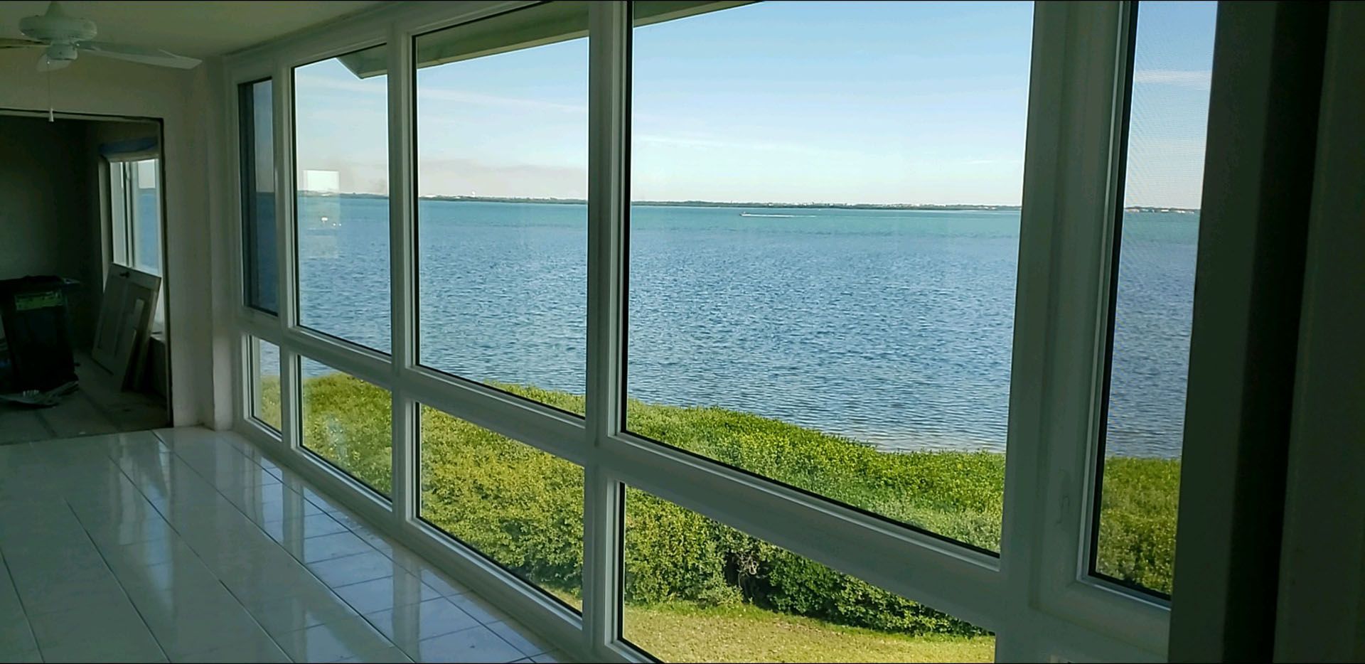 A room with a lot of windows overlooking a body of water.