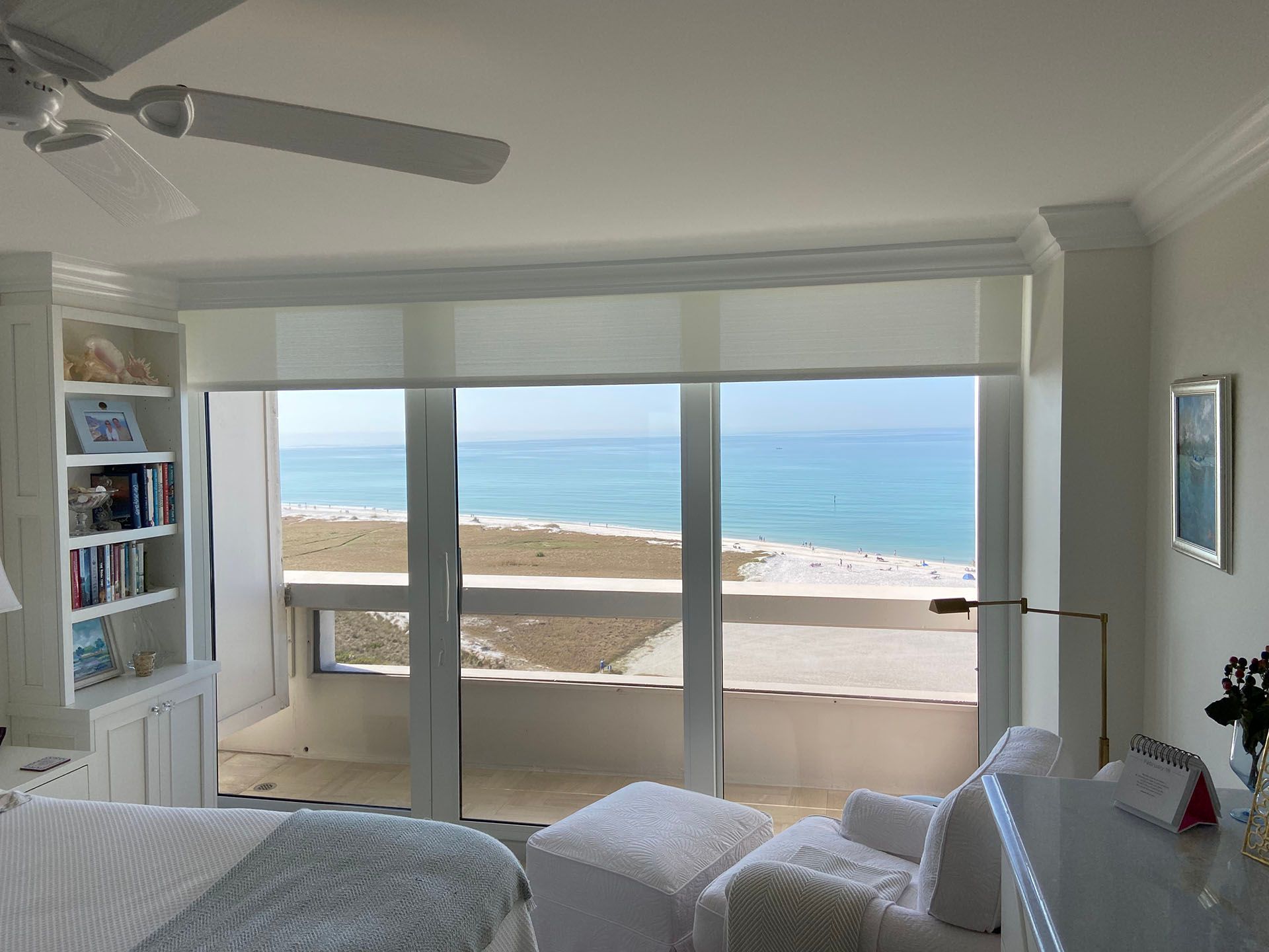 A bedroom with a view of the ocean and a ceiling fan.